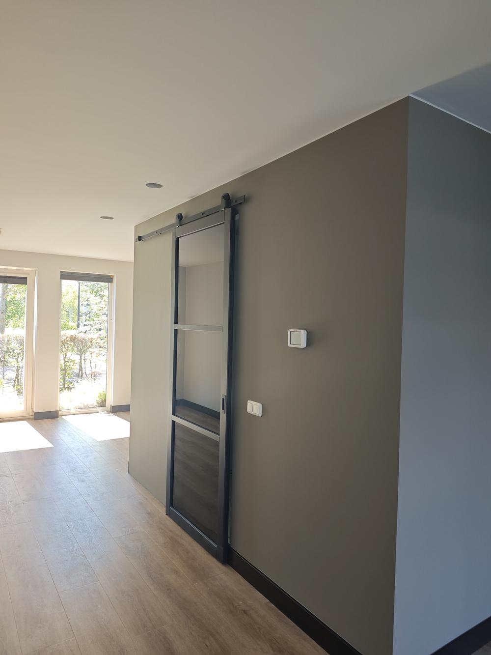 Taupe accentwand met stalen schuifdeur, strak sauswerk
